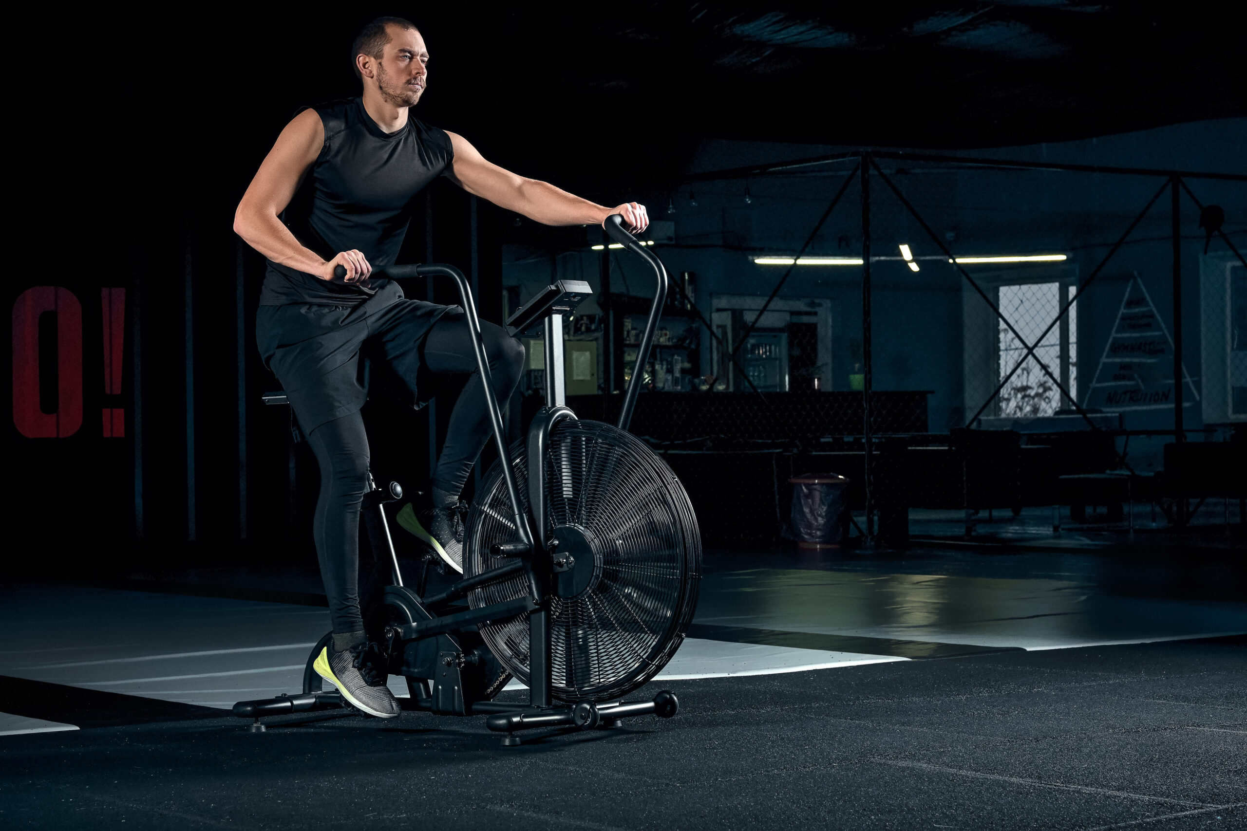 Male using air bike for cardio workout at cross training gym.